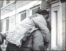 A woman being carried into the hospital for gunshot wounds inflicted by a Japanese soldier who threatened to rape her. Photo taken by Forster.